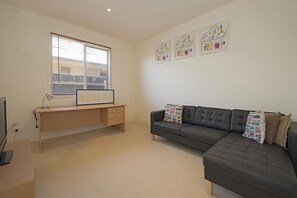 A modern living room with a desk, a leather sofa, and artwork on the walls.