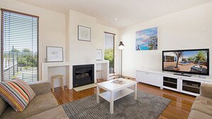 A modern living room with a fireplace, sofa, coffee table, and a television.