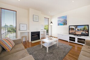 A modern living room with a fireplace, sofa, coffee table, and a television.