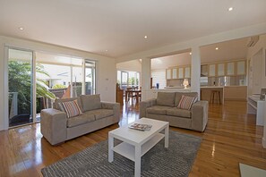 A spacious living area with two sofas, a coffee table, and a kitchen in the background. - KaniCoast  Sorrento holiday home with Spa (SORRENTO)
