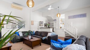 Ein modernes Wohnzimmer mit einem braunen Ledersofa, einem Holztisch und einer Treppe, die zu einer oberen Ebene führt.