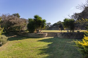 A landscaped garden with a grassy area, stone planters, and a variety of trees.