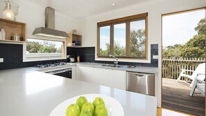 Una cucina moderna con una grande isola, elettrodomestici in acciaio inossidabile e vista sull'esterno.