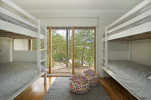 A room with bunk beds, a large window, and a colorful polka-dotted chair. - Treetops Coastal Family Retreat in Sorrento (SORRENTO)