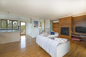 A modern living room with a sofa, a television, and a fireplace. - Treetops Coastal Family Retreat in Sorrento (SORRENTO)