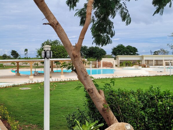 A pool area with a covered seating area, a water slide, and a well-maintained lawn.