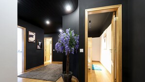 A hallway with wooden flooring, a dark wall, and a potted plant with purple flowers. - Luxurious & Modern central apt w / 4 rooms, private terrace and 2 parking spaces (Lisboa)