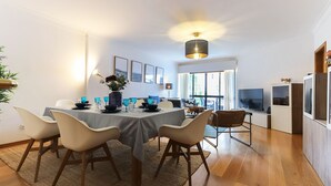 A modern dining area with a table set for four, surrounded by chairs, a vase with flowers, and a ceiling light fixture. - Luxurious & Modern central apt w / 4 rooms, private terrace and 2 parking spaces (Lisboa)