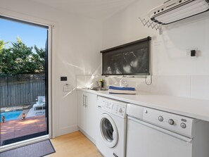 A compact laundry room with a washing machine, a drying rack, and a window overlooking a backyard. - Corfu Sorrento with magnesium pool (SORRENTO)