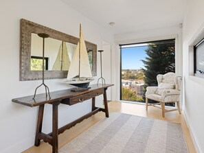 A room with a wooden console table, a sailboat model, a chair with writing, and a large window with a view. - Corfu Sorrento with magnesium pool (SORRENTO)