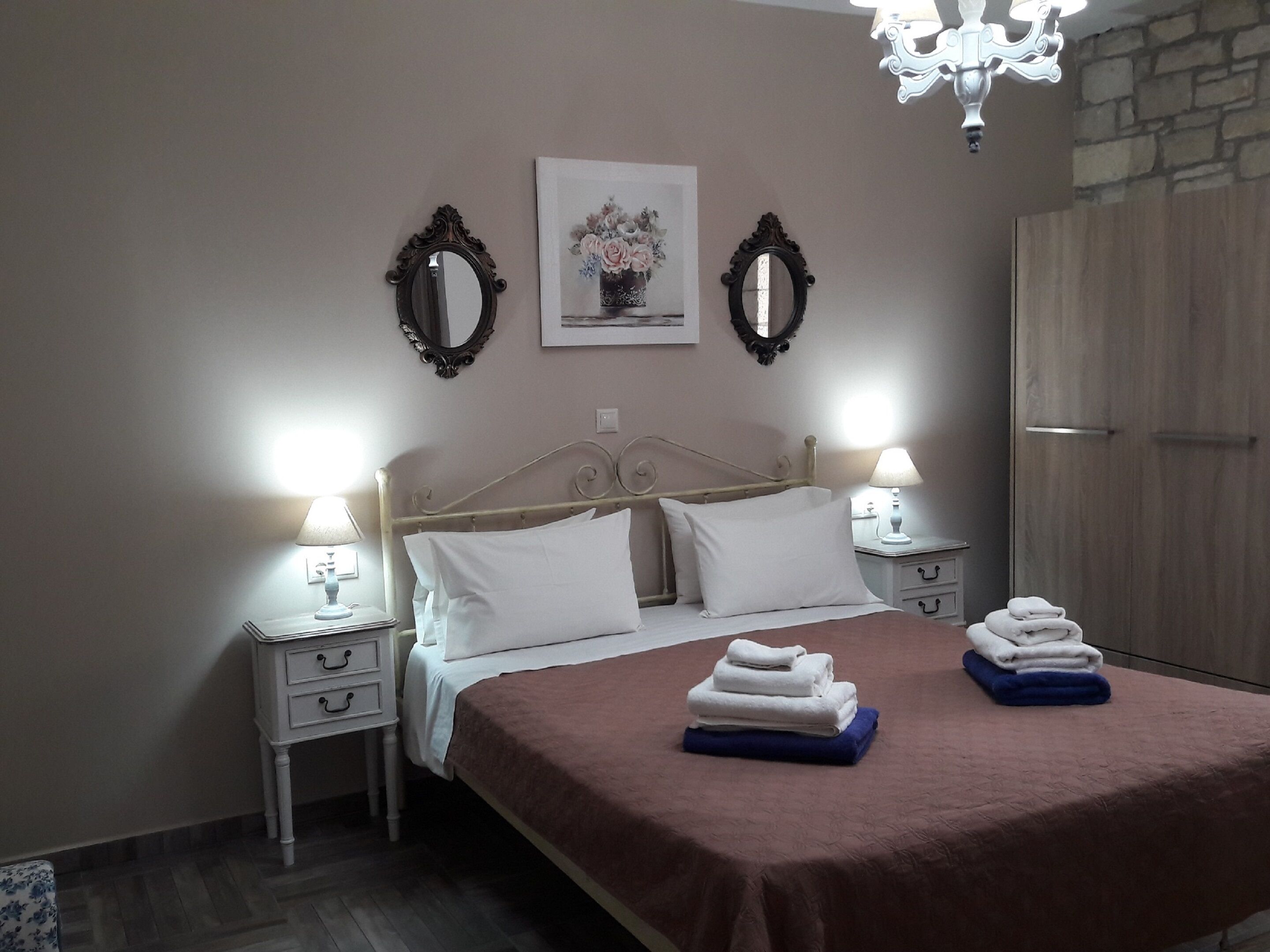 Un dormitorio ordenado con cama, dos mesitas de noche, un tocador, un espejo, un marco de fotos y un armario.