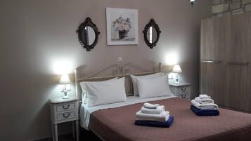 Un dormitorio ordenado con cama, dos mesitas de noche, un tocador, un espejo, un marco de fotos y un armario.