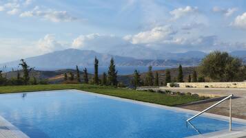 Una piscina con vista chiara sulle montagne e un corpo d'acqua sullo sfondo.