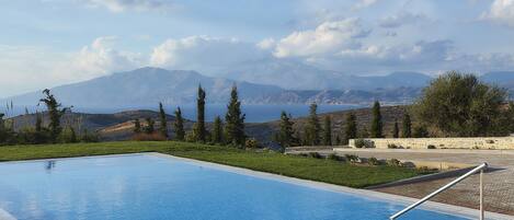 A swimming pool with a clear view of mountains and a body of water in the background.