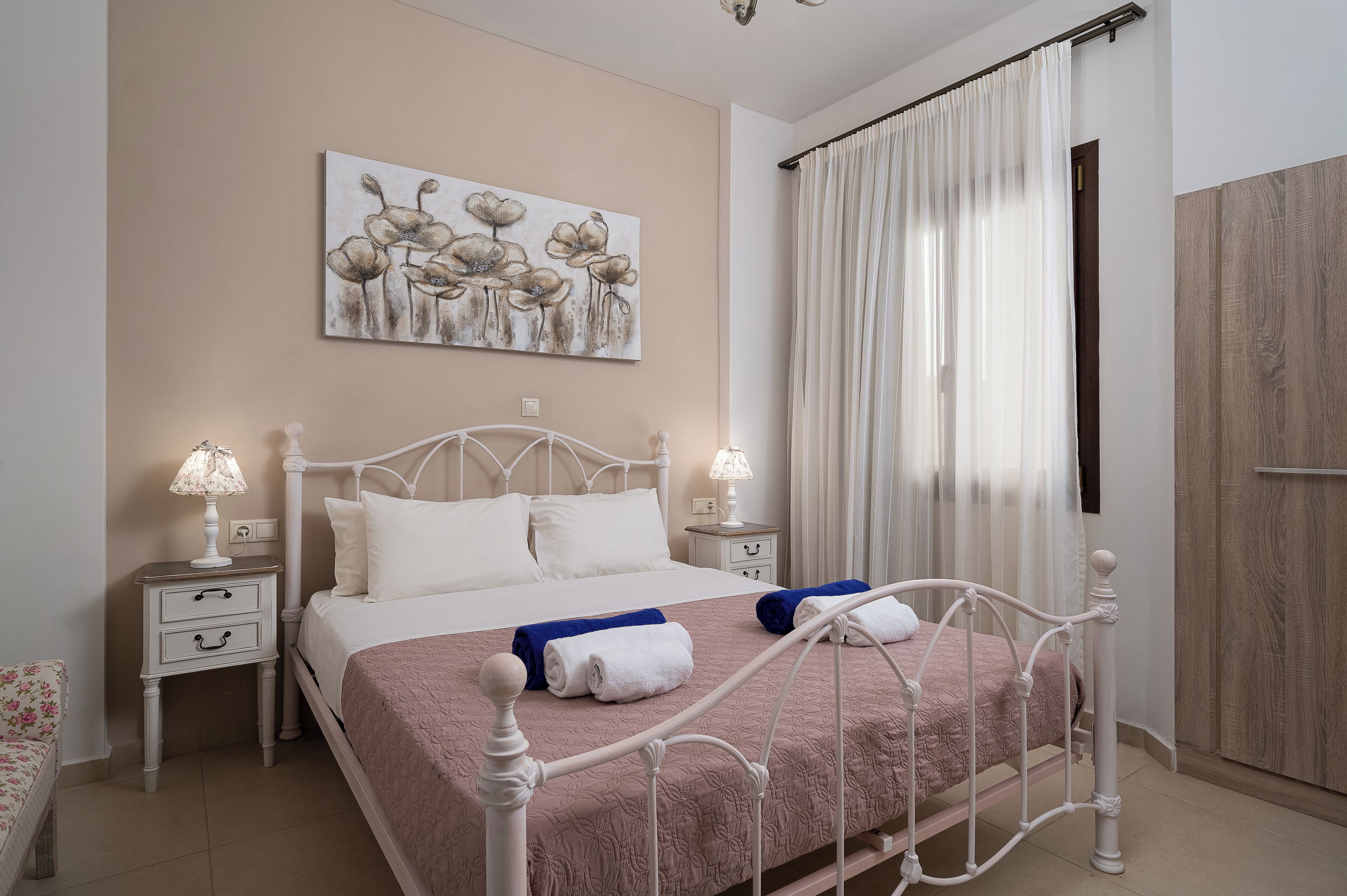 Un dormitorio ordenado con cama, mesitas de noche, un cuadro y un armario.
