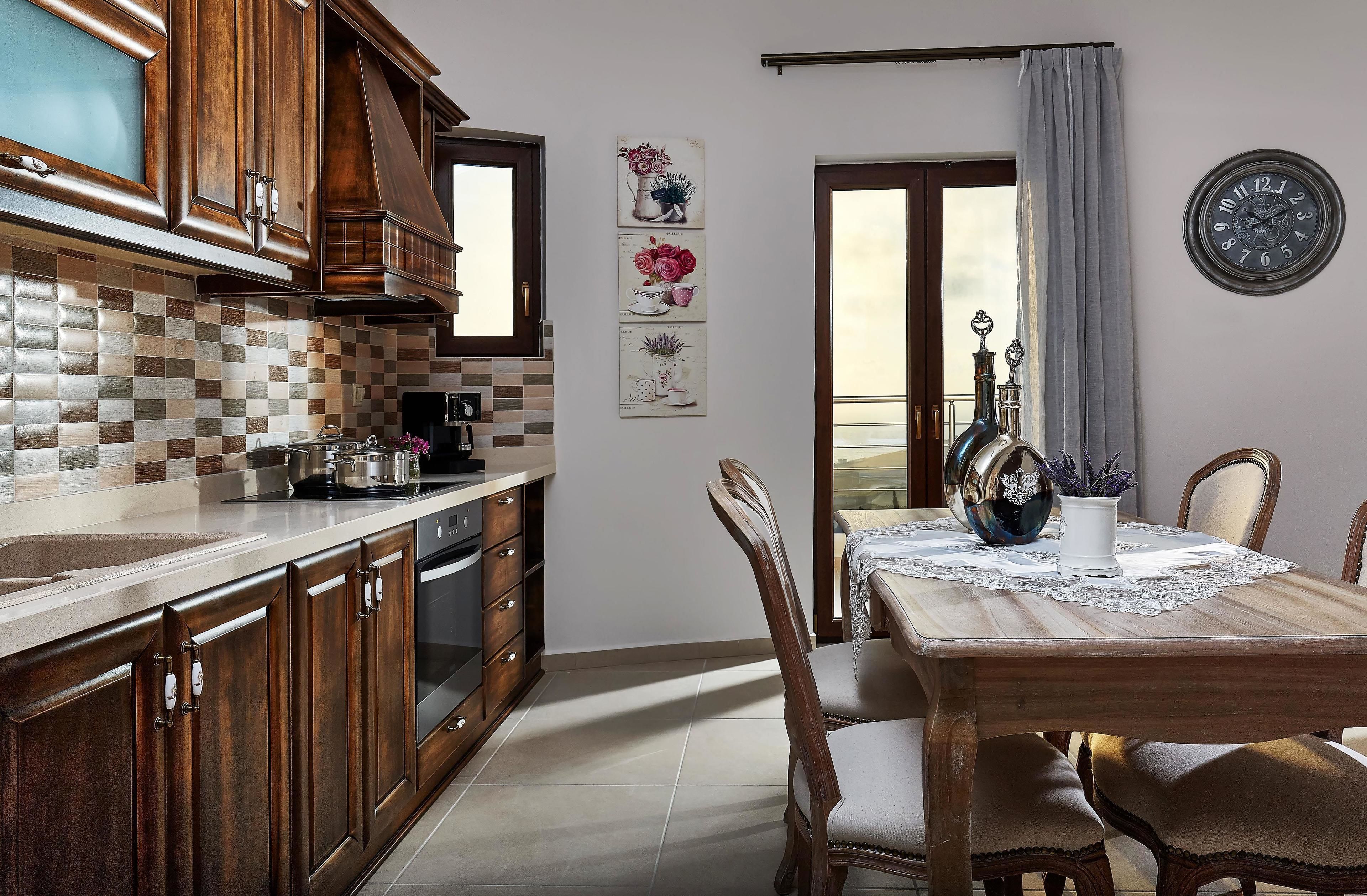 Une cuisine avec des meubles de rangement en bois, un pare-feu en carreaux et un coin repas comprenant une table et des chaises.