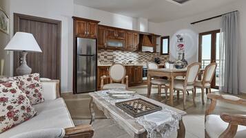 A spacious living area with a sofa, a dining table with chairs, a kitchen with wooden cabinets, and a refrigerator.