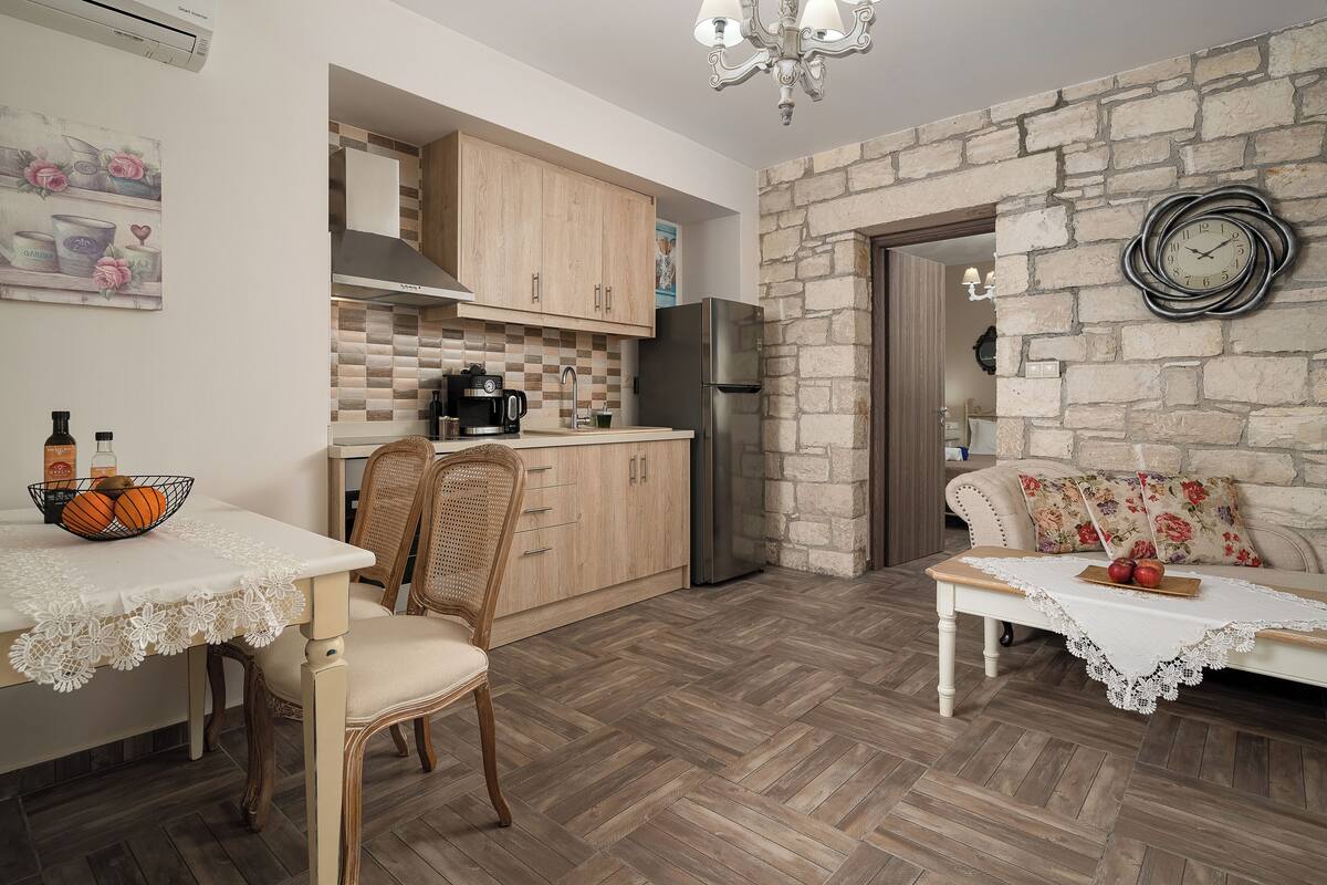 Une cuisine compacte avec des meubles en bois, un réfrigérateur en acier inoxydable et un mur en pierre.