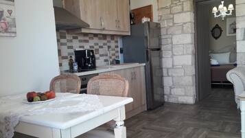 A compact kitchen with wooden cabinets, a refrigerator, and a dining area with a table and chairs.