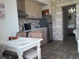 A compact kitchen with wooden cabinets, a refrigerator, and a dining area with a table and chairs.