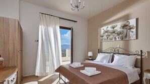 Ein Schlafzimmer mit Bett, Nachttisch, Vorhängen am Fenster, einem Bild an der Wand und Blick ins Freie.