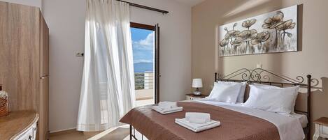 Un dormitorio con cama, mesita de noche, cortinas en la ventana, un cuadro en la pared y vistas al exterior.