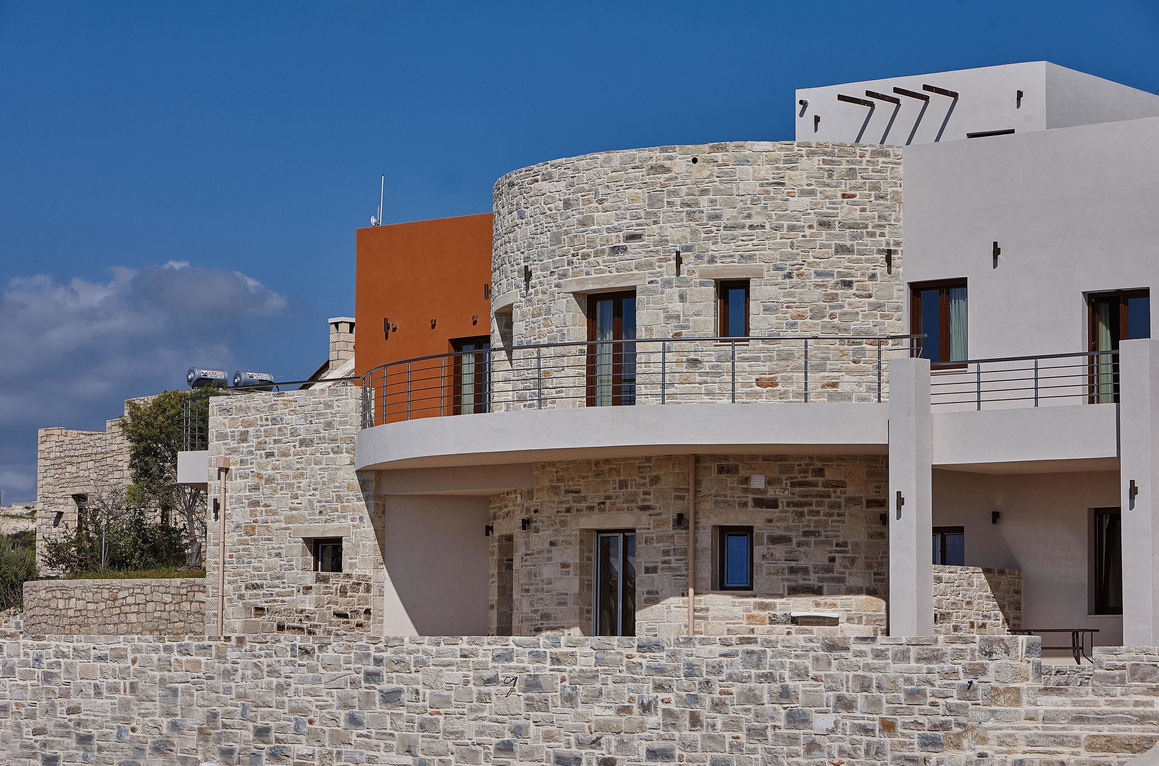 A modern building with stone facade, balconies, and a flat roof.