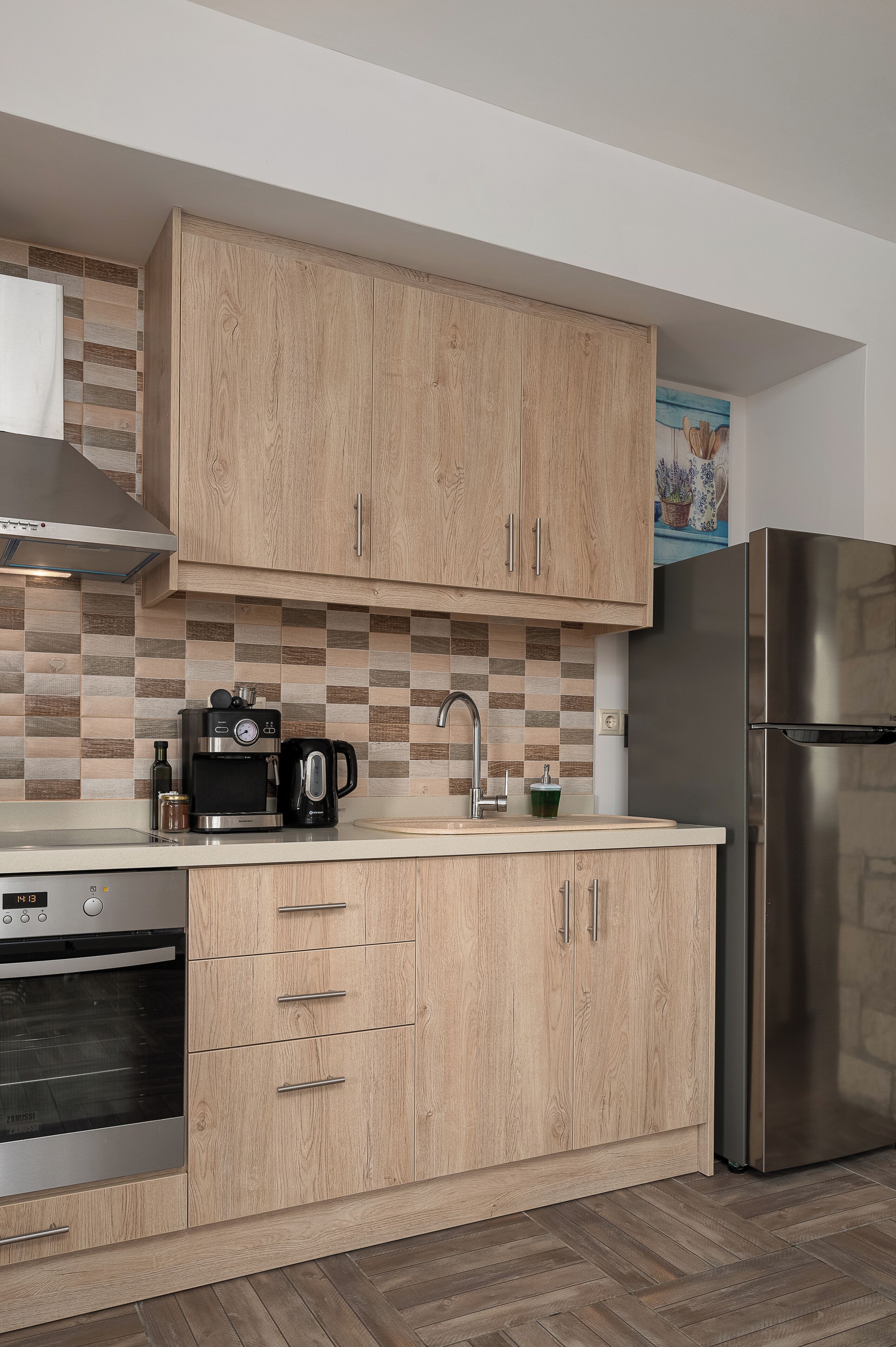 Eine Küche mit Holzschränken, einem Edelstahlkühlschrank, einem Einbauofen und einer Kaffeemaschine.