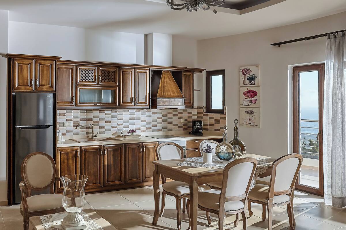Une cuisine moderne avec des meubles en bois, un four encastré et un coin repas avec une table dressée pour quatre personnes.