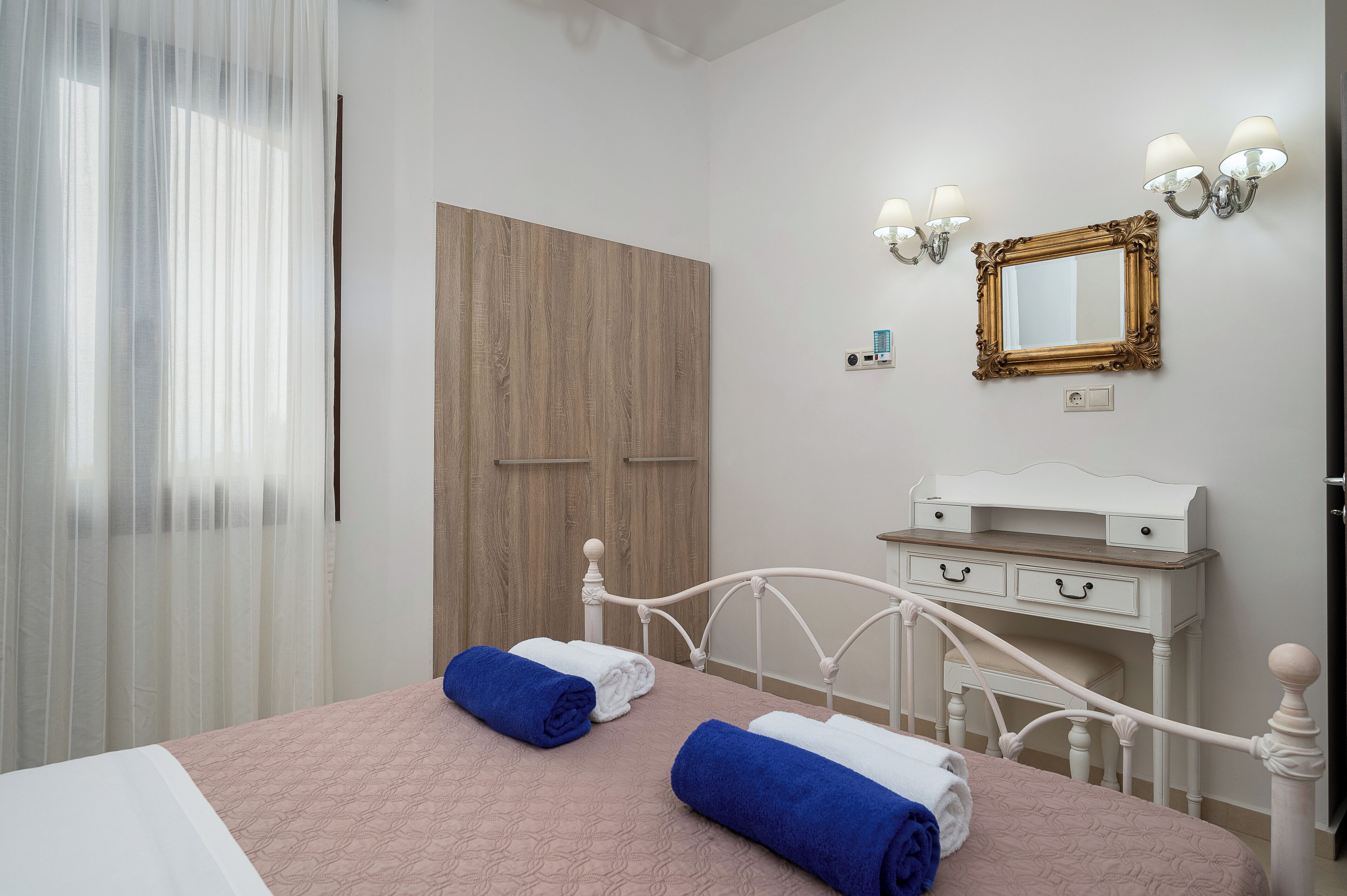 Una camera da letto con un letto, un comodino, una cassettiera, uno specchio e un armadio.