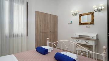 Una camera da letto con un letto, un comodino, una cassettiera, uno specchio e un armadio.