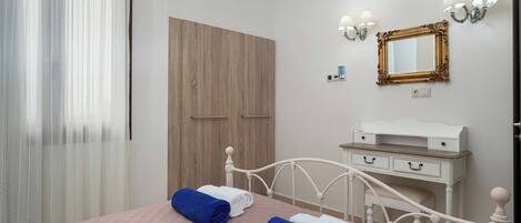 A bedroom with a bed, a nightstand, a dresser, a mirror, and a wardrobe.