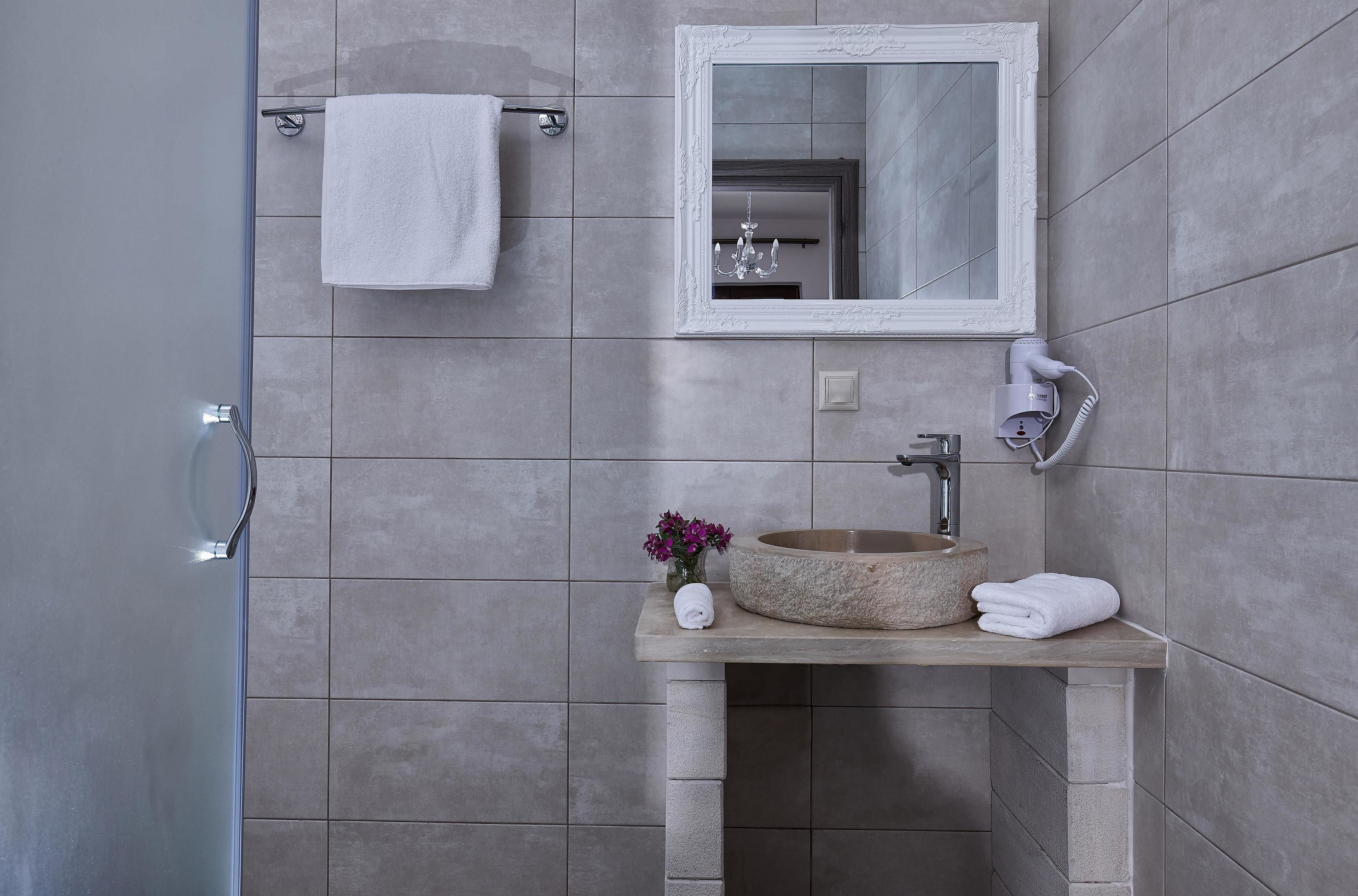 Un baño con un lavabo de piedra, una toalla blanca, un espejo y un secador de pelo.