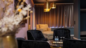A modern hotel room with a seating area featuring black velvet chairs, a small round table with a tray, and a sofa with a beige cushion. - Waldhotel Riesebusch (Bad Schwartau)