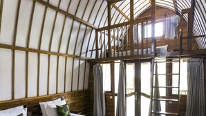 A room with a bunk bed, wooden beams, and a window with curtains. - Cotton Tree Cottages (Gili Trawangan)