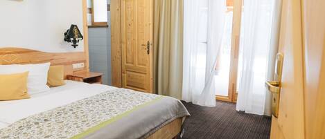 A hotel room with a bed, wooden wardrobe, and a window with curtains.