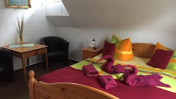 Ein Schlafzimmer mit einem hölzernen Bett, einem Schreibtisch, einem Stuhl, einem Nachttisch mit Lampe und einem Gemälde an der Wand.