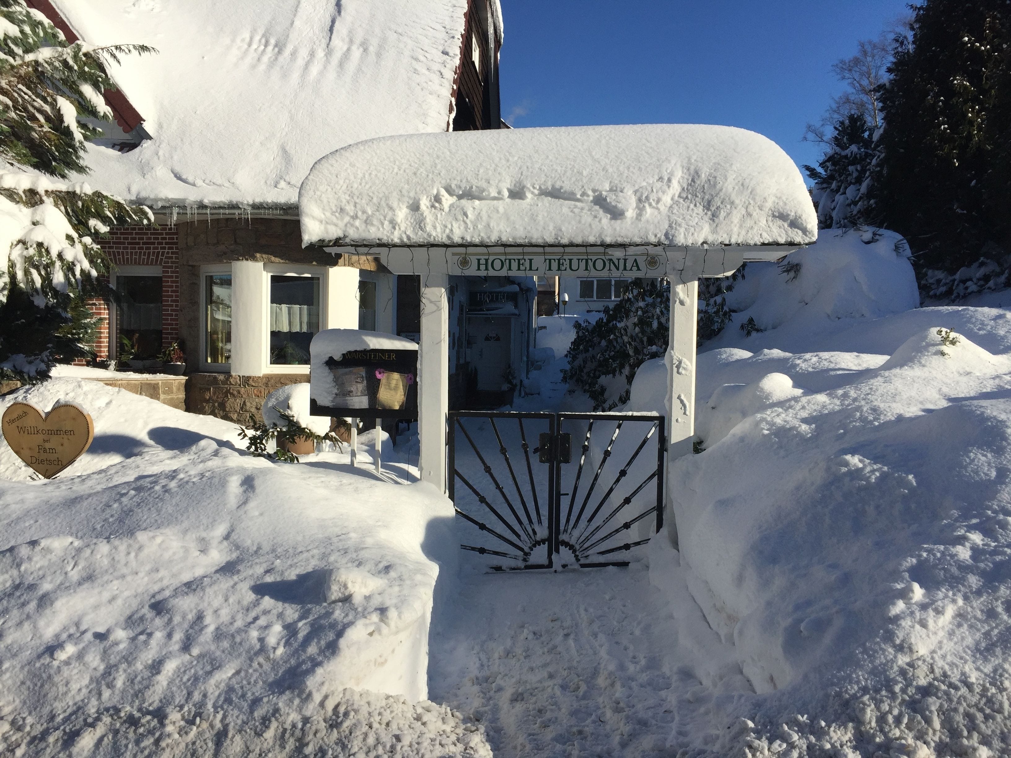 A snow-covered hotel entrance with a sign that reads "HOTEL TEUTONIA".