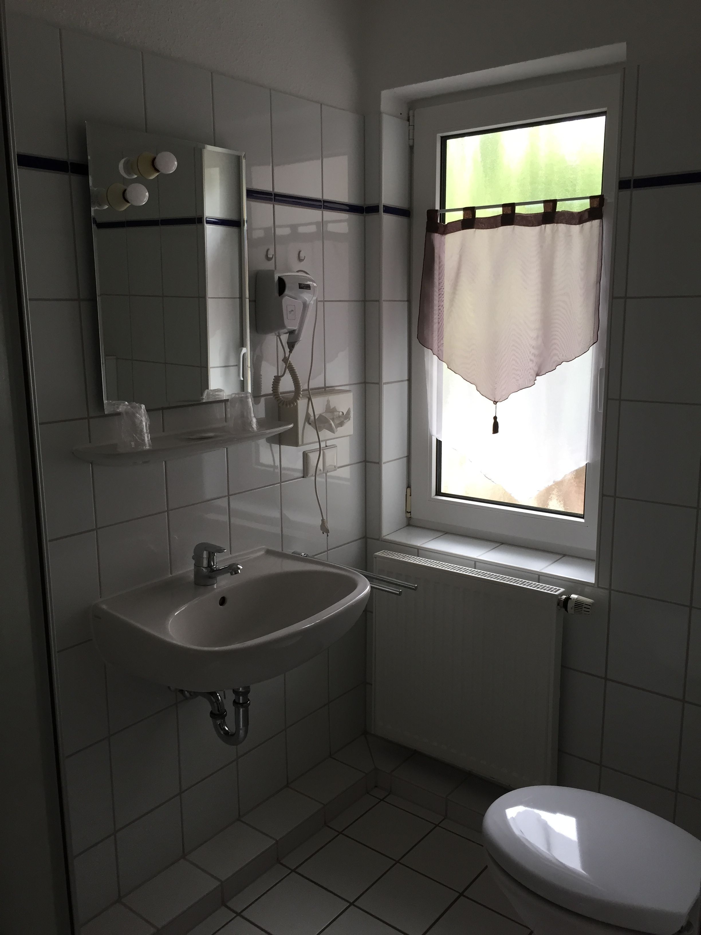 A bathroom with a white sink, a mirror, a hairdryer, and a toilet.