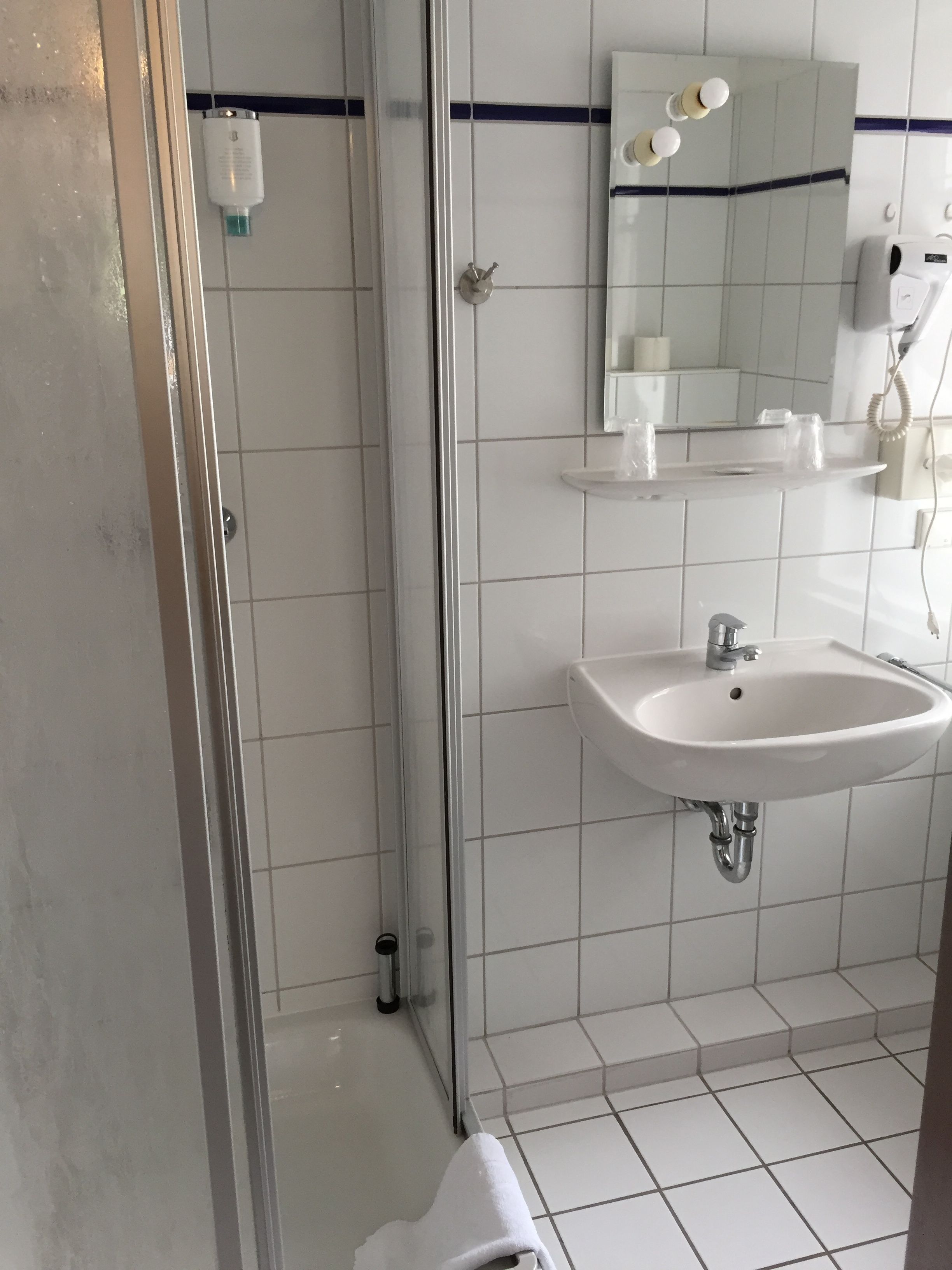 Une salle de bain avec une douche à parois de verre, un lavabo blanc et un miroir au-dessus du lavabo.