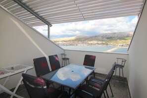 Een balkon met een tafel en stoelen, met uitzicht op een waterpartij en een stad.
