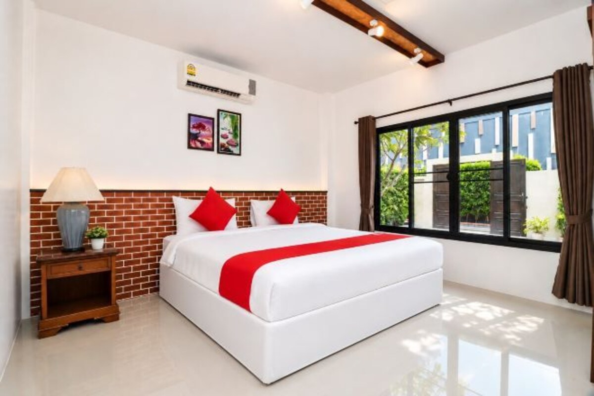 A hotel room with a large bed, a nightstand, a lamp, and a window with curtains.