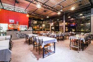 An indoor dining area with tables and chairs, a counter with a beverage display, and a mural on the wall. - Baan Noppadol Hua Hin Loft Hotel (Hua Hin)