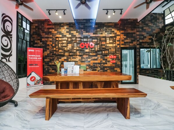 A reception area with a wooden bench, a wall with a 'OYO' sign, and a poster promoting the OYO app. - Baan Noppadol Hua Hin Loft Hotel (Hua Hin)