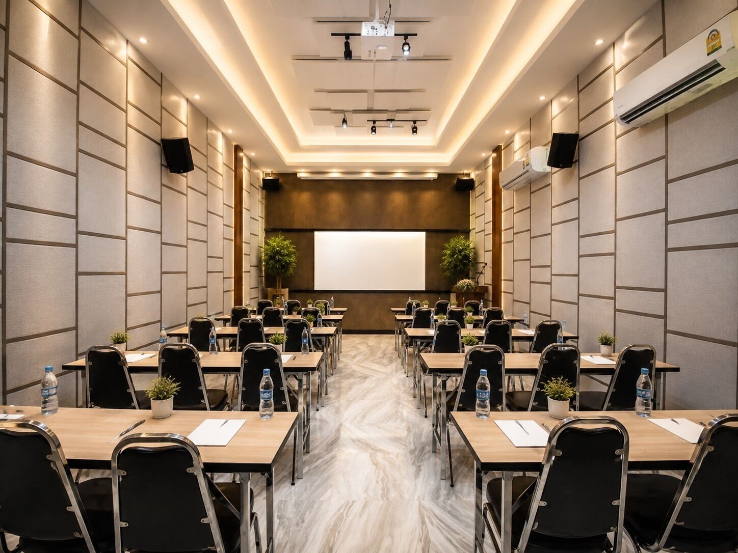 Una sala conferenze con diversi tavoli e sedie, uno schermo per proiettore e un pavimento in marmo.