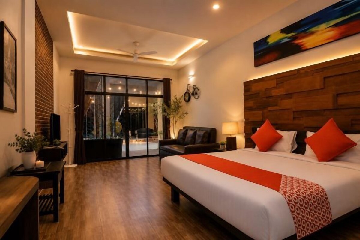 Ein Hotelzimmer mit einem großen Bett, einem Holzkopfende, einem Schreibtisch und einer Glastür zum Außenbereich.