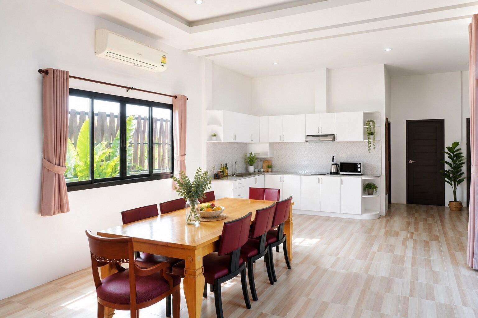 A modern kitchen with white cabinets, a dining table with chairs, and a view of greenery outside.