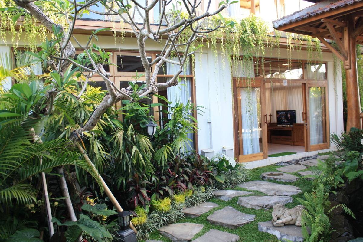 Un jardín con un camino de piedra que conduce a una estructura de madera con un televisor.
