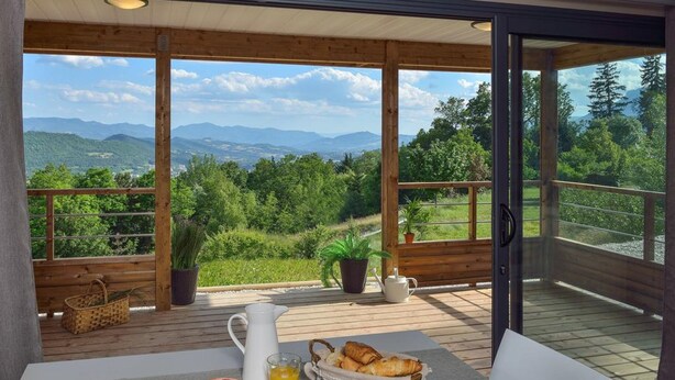 Un coin petit-déjeuner aménagé sur une terrasse en bois, offrant une vue imprenable sur les montagnes.