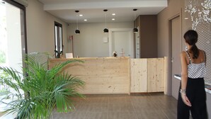 Una zona de recepción con mostrador de madera, una planta en maceta y un diseño moderno de techo.